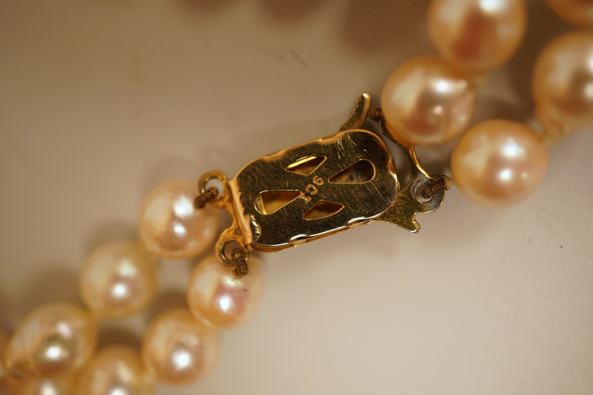 A modern twin strand cultured pearl choker necklace, with an engraved 9ct clasp, approx. 40cm, together with a cultured pearl bracelet, with diamond chip set butterfly shaped 14k clasp, 18cm, with four fluted yellow meta